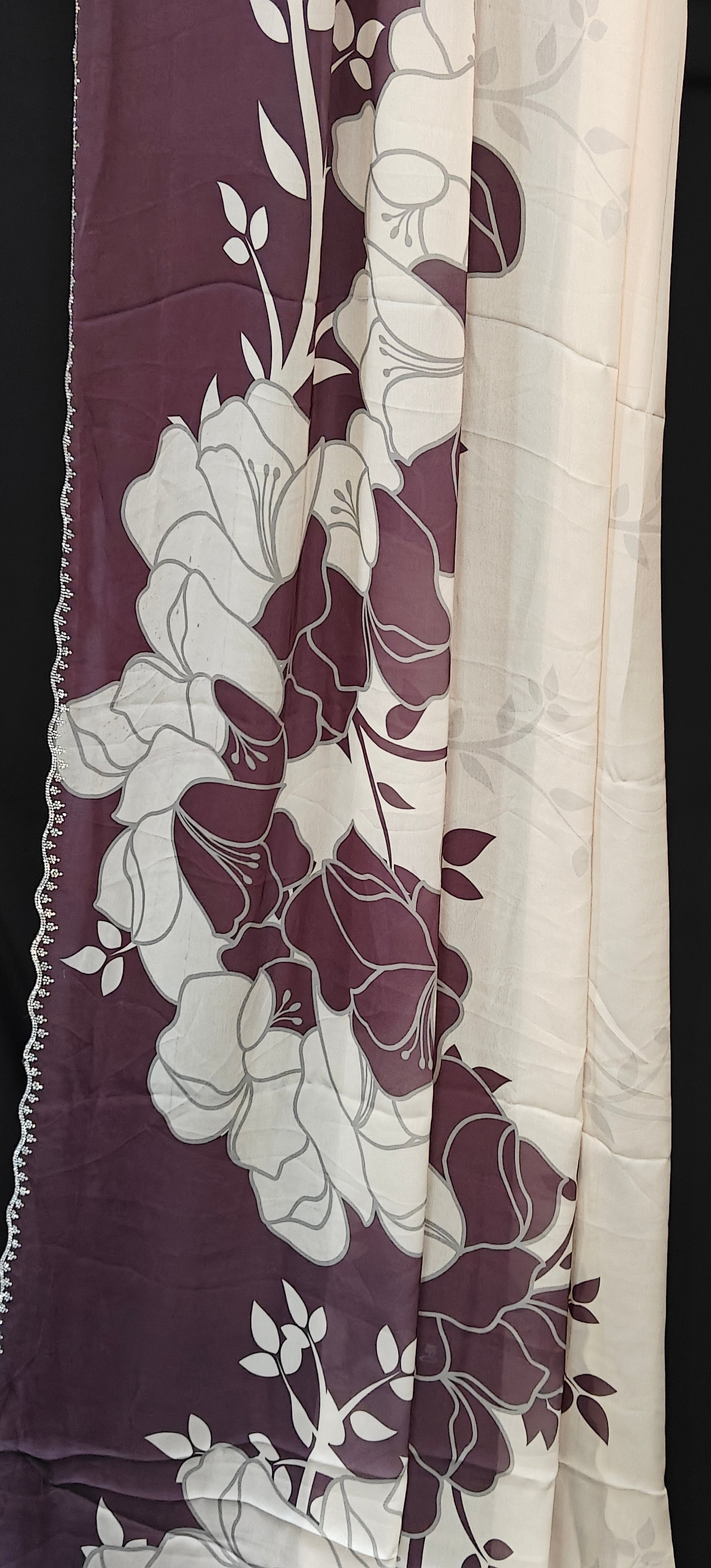 Wine red satin saree with large floral patterns and scalloped border, stylish festive saree with glossy drape.
