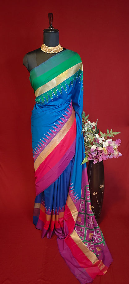 soft silk saree in sapphire blue with multicolor border and dotted digital print, styled on mannequin with flower vase against red background.
