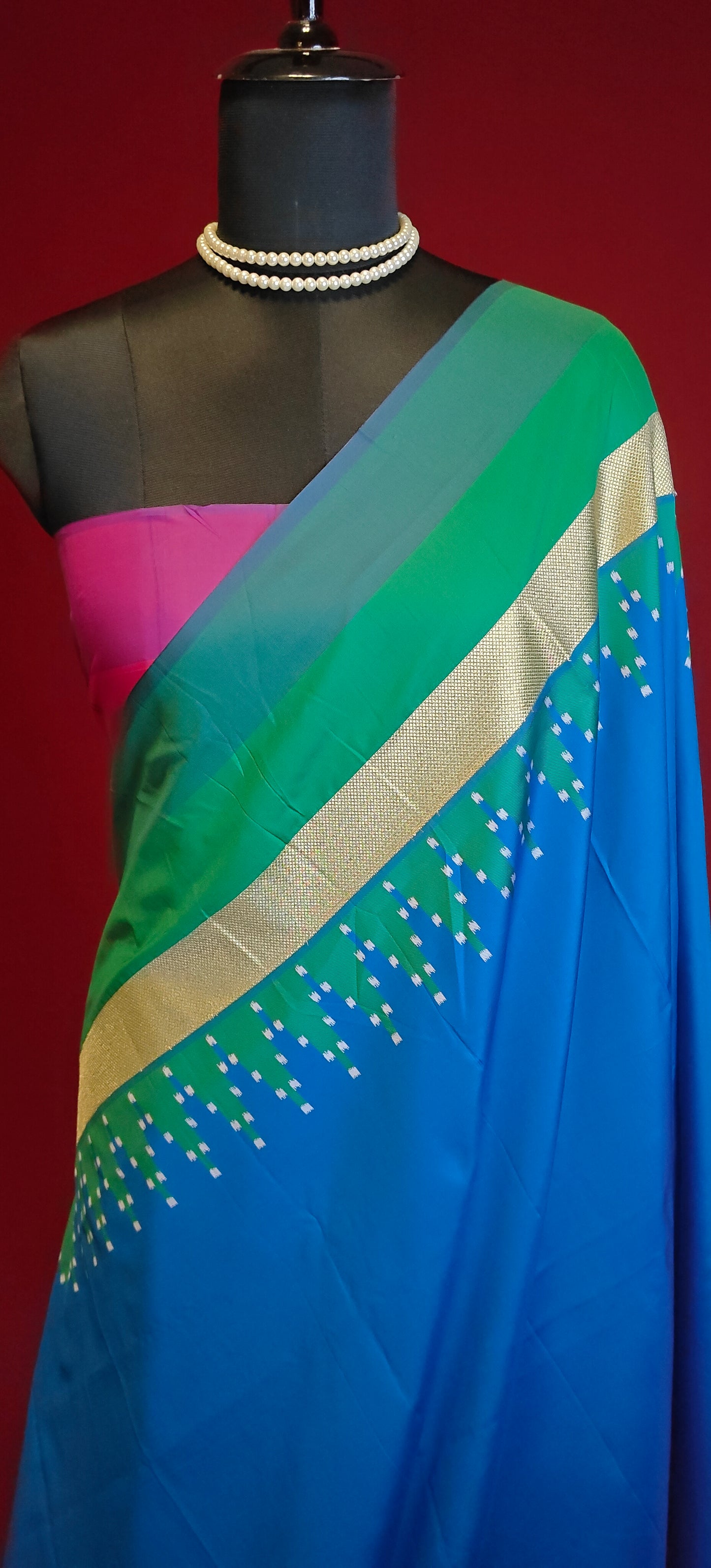 soft silk saree in sapphire blue with multicolor border and dotted digital print, styled on mannequin showcasing the blouse piece against red background.