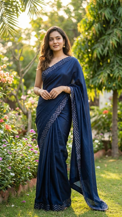 Woman in a Blue silk saree with metallic zigzag border in gold and silver standing in a garden