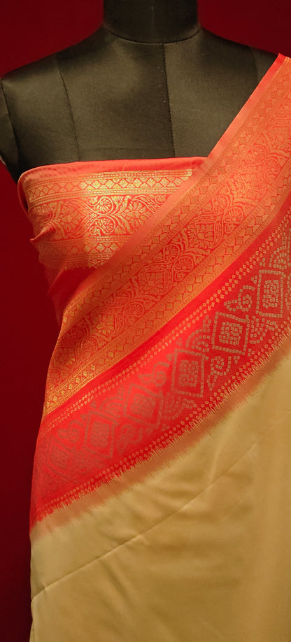silk cream saree with red Zari border and golden motifs, styled on mannequin showcasing the pink blouse piece against red background.