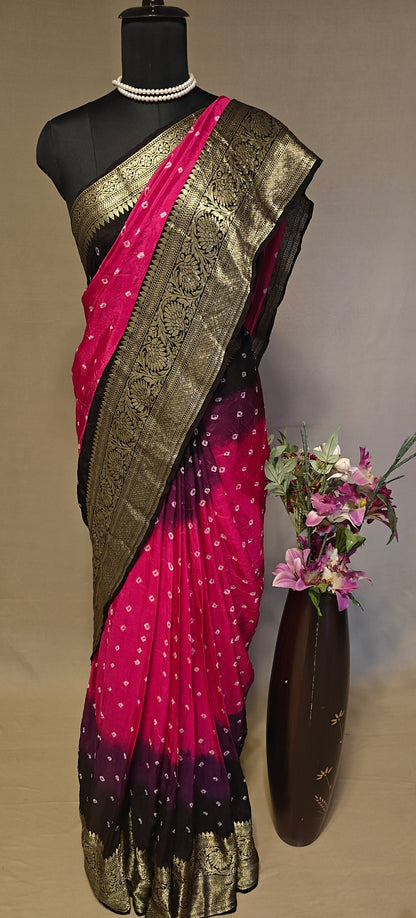 Magenta silk saree with broad golden zari border, styled on mannequin with a vase of flowers in the background.