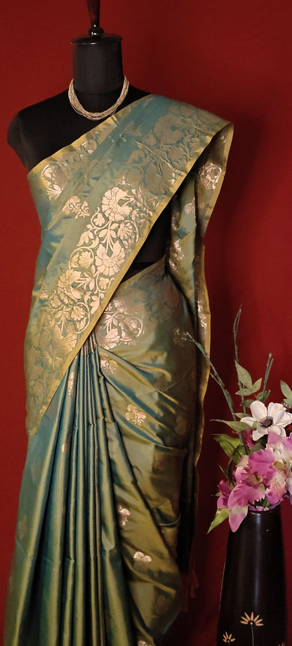 Emerald green silk blend saree with intricate woven detailing and elegant drape on a mannequin with a red background