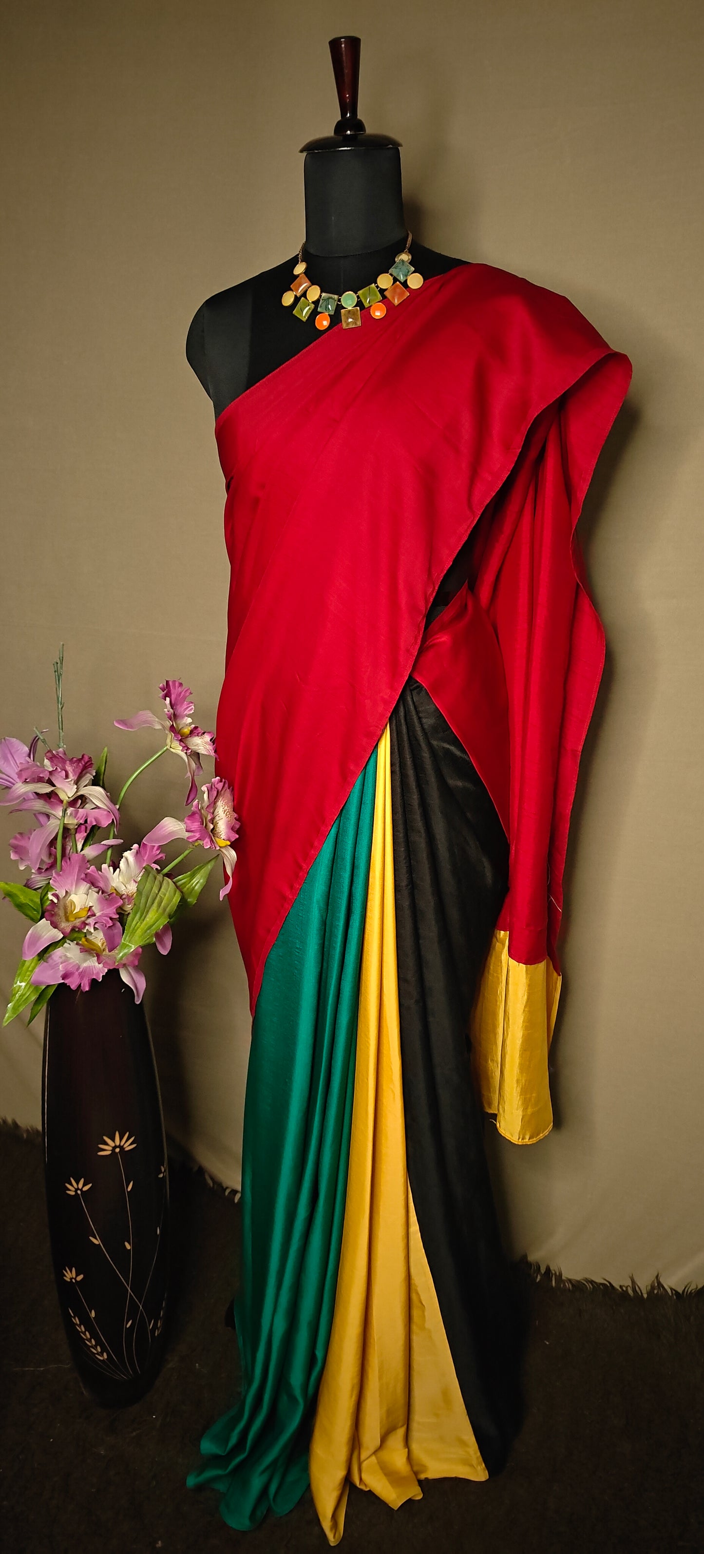 Strawberry silk saree with multicolor panelled design in red, green, black, yellow, and gold, displayed on mannequin with statement necklace