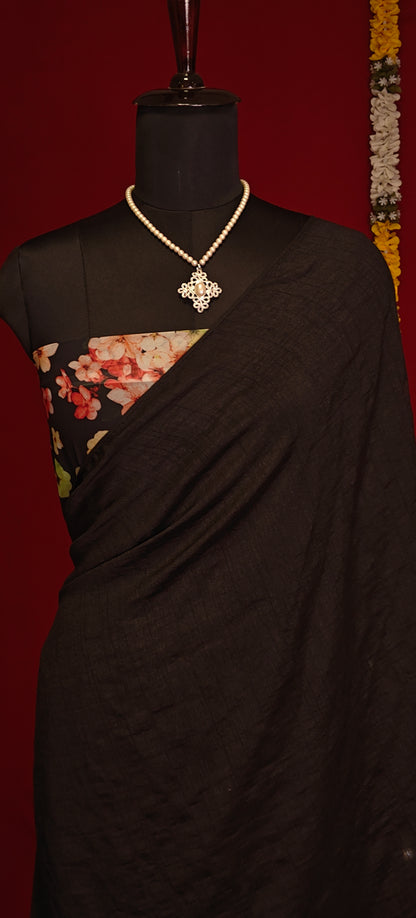 Black strawberry silk saree with soft sheen and elegant drape, styled on mannequin showcasing the blouse piece against a red background.