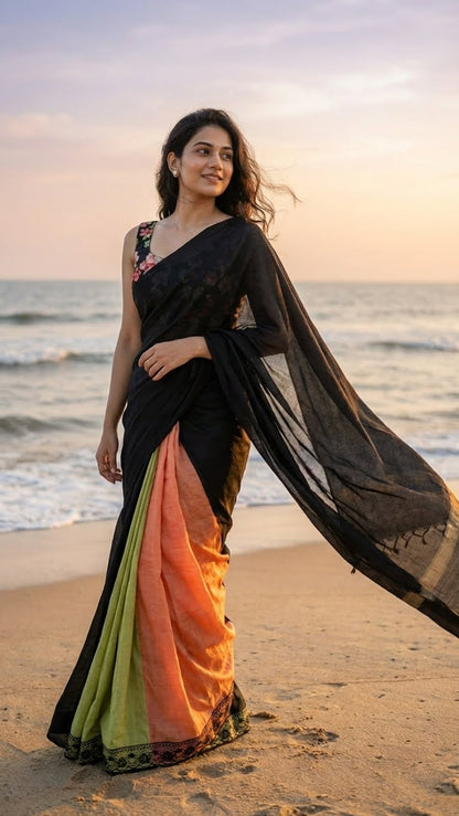 Woman in a black strawberry silk saree with soft sheen and elegant drape standing on a beach with ocean in the background