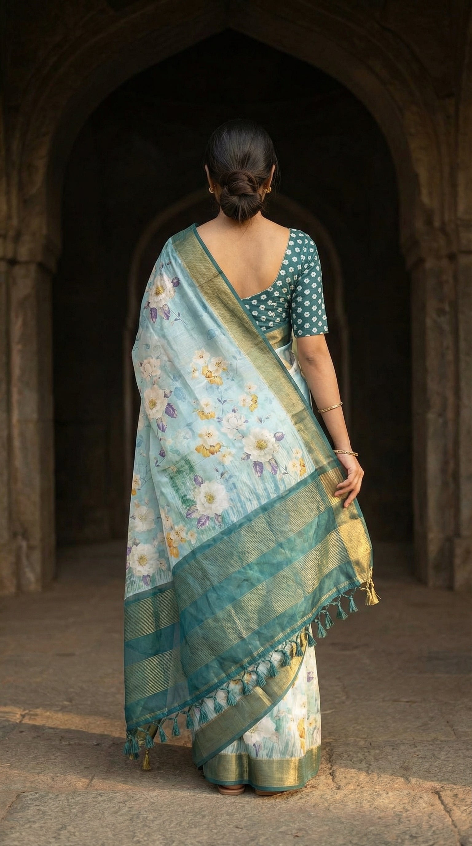 Woman wearing Sea green viscose silk saree with floral print, standing back-facing towards an architectural setup.