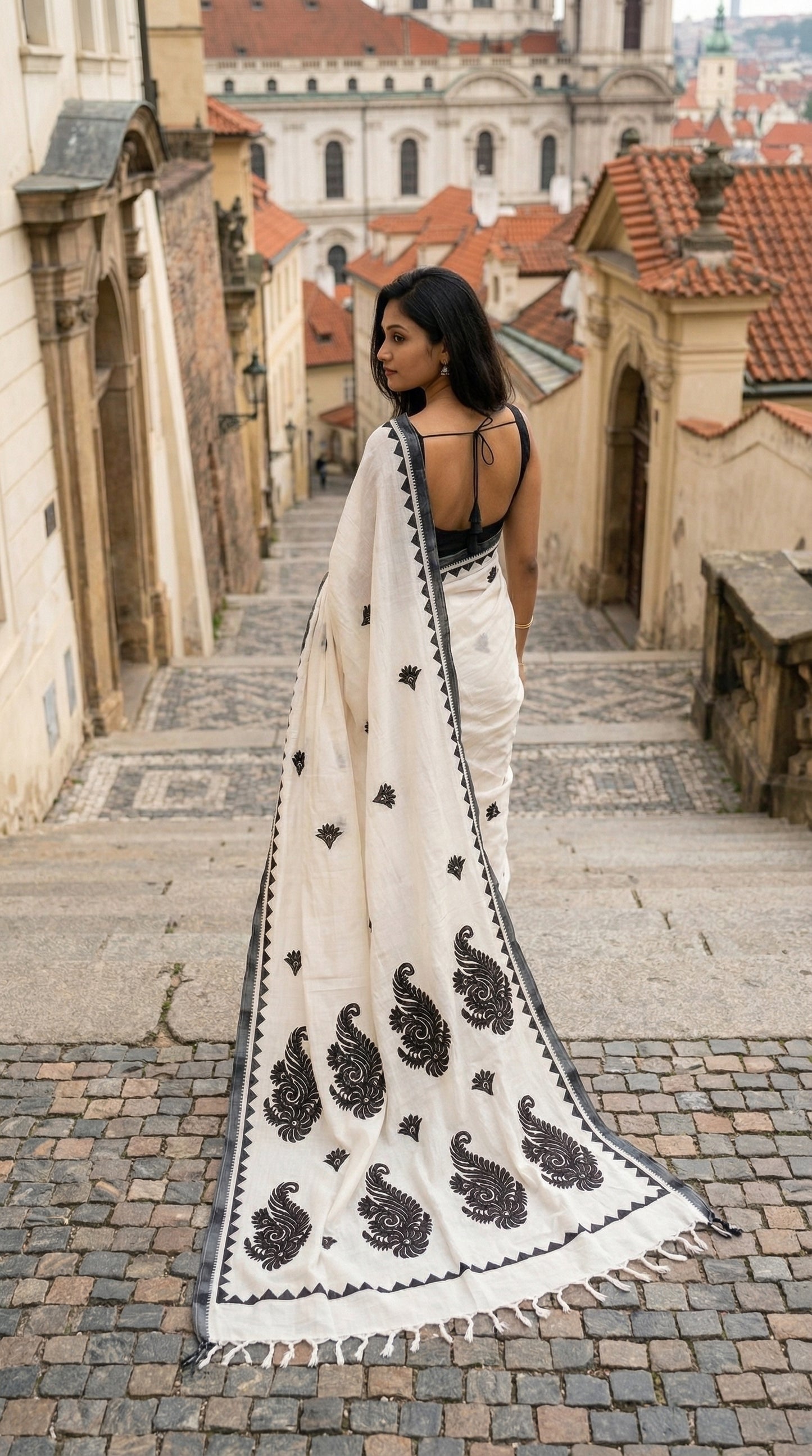 Woman in a white-black-cotton-linen-saree, walking through a European city street.