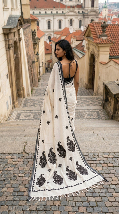 Woman in a white-black-cotton-linen-saree, walking through a European city street.