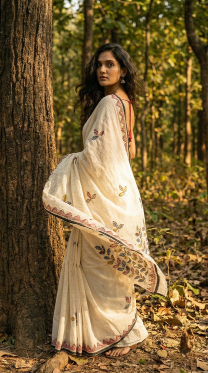 Woman in a white-black-kota-doria-saree, standing in a forest.