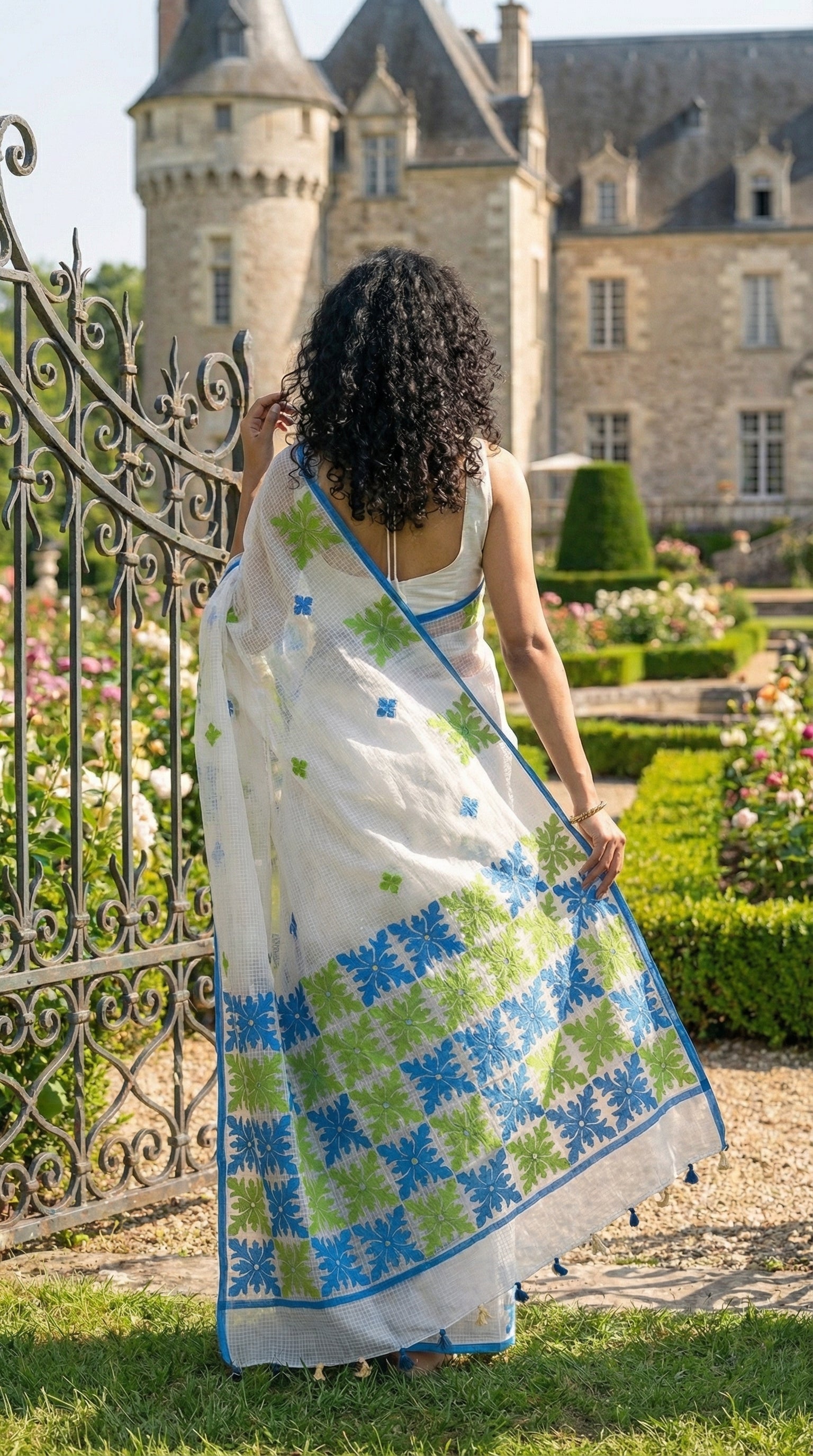 Woman in a white-green-blue-applique-kota-saree, standing in front of a castle.