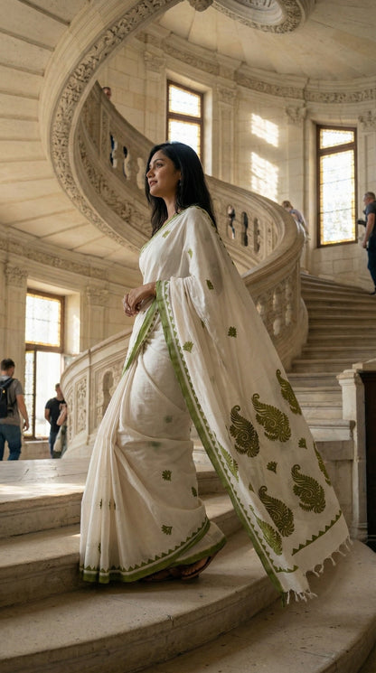 Woman in a white-green-cotton-linen-saree, standing on a staircase in an elegant building.