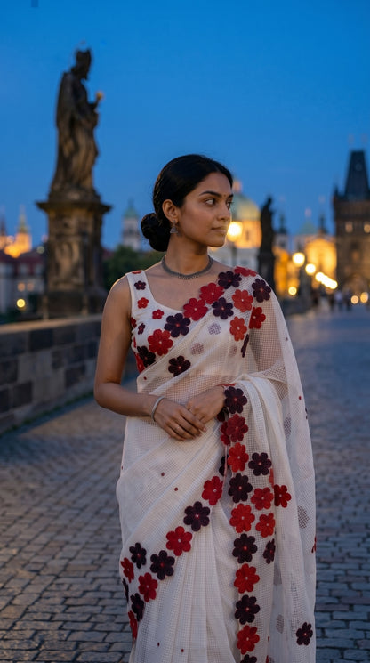 Woman in a white-maroon-brown-mirror-saree, standing on a bridge at dusk.