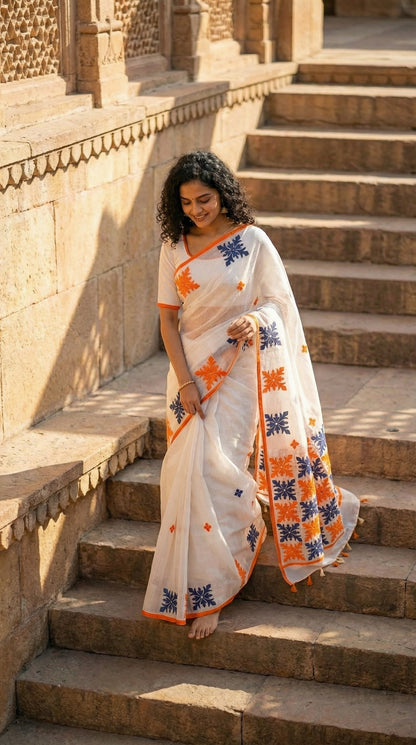 Woman in a white-orange-grey-applique-kota-saree, standing on stone steps with architectural background