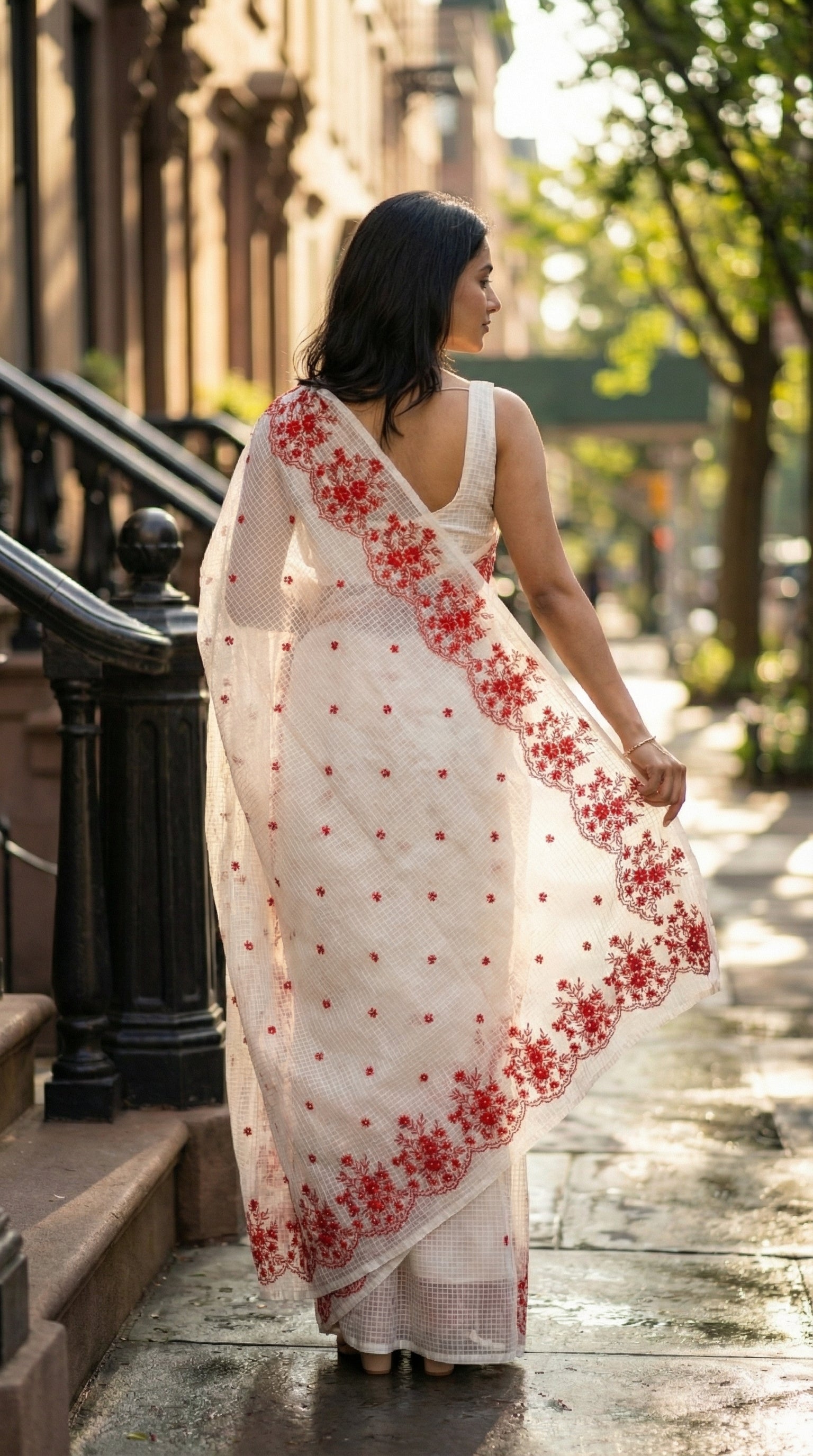 Woman in a white-resham-kota-cotton-saree-red-embroidery, walking on a sidewalk.